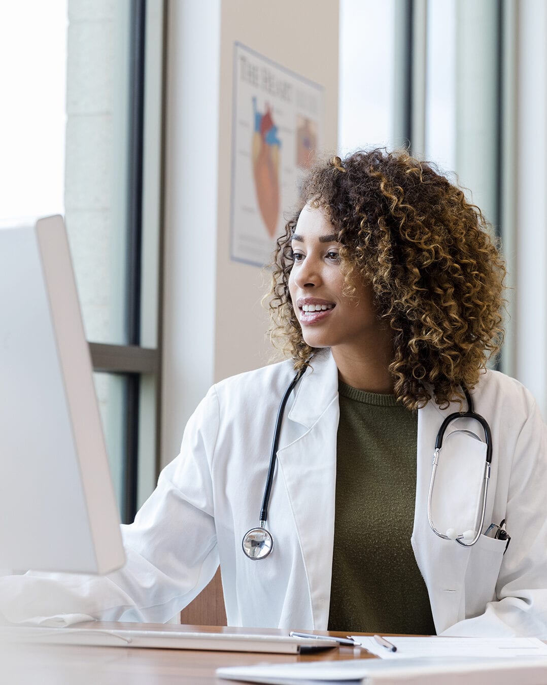 Doctor reviews patient records on desktop PC