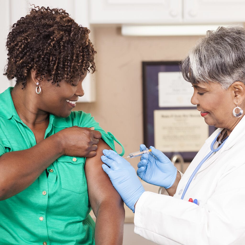 Doctor or nurse gives flu vaccine to patient at clinic.